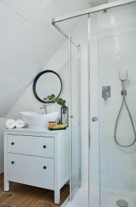 biała łazienka z umywalką i prysznicem w obiekcie Noclegi Pod Sokołem w mieście Sokółka