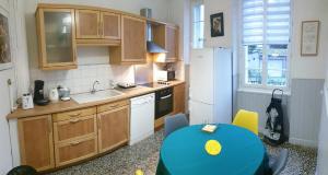 uma cozinha com uma mesa e uma cozinha com um frigorífico em L Hôte Rutène em Rodez