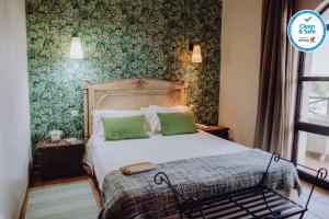 a bedroom with a bed with green wallpaper at Hotel Parque das Laranjeiras in Vilamoura