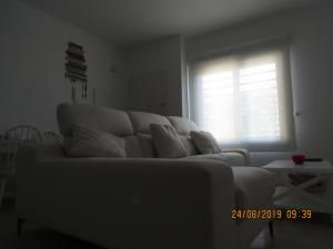 a white couch in a living room with a window at Apartamentos Cachón in Zahara de los Atunes