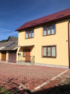 ein gelbes Haus mit rotem Dach und einer steinernen Einfahrt in der Unterkunft Затишна оселя in Mischhirja
