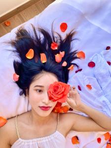 uma mulher deitada numa cama com uma flor no cabelo em Sweet Dream Hotel & Villa em Da Lat