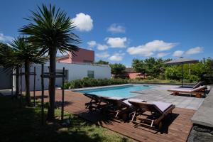 a swimming pool with chairs and a palm tree at Quinta dos Peixes Falantes in Ribeira Grande