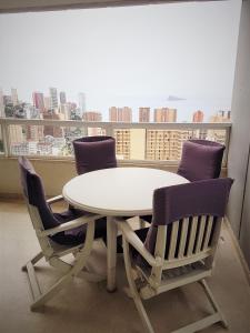 una mesa y sillas blancas en una habitación con ventana en GEMELOS 22 APARTMENTS - Benidormland, en Benidorm