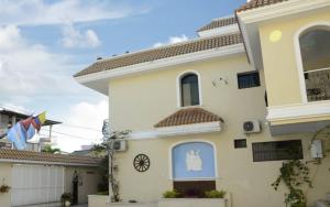 a white house with a clock on the side of it at Hotel Casa Del Rio Guayas in Guayaquil