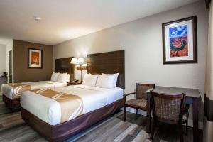 a hotel room with two beds and a table and chairs at Quality Inn Pinetop Lakeside in Pinetop-Lakeside