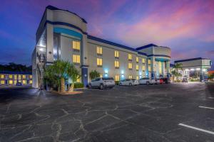 un grand bâtiment avec des voitures garées dans un parking dans l'établissement Clarion Inn & Suites Central Clearwater Beach, à Clearwater