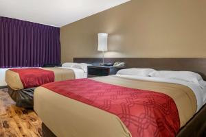 two beds in a hotel room with purple curtains at Econo Lodge Sebring in Avon Park