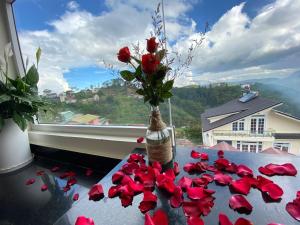 um vaso com flores vermelhas numa mesa com uma janela em Sweet Dream Hotel & Villa em Da Lat