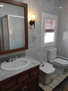 ein Badezimmer mit einem Waschbecken, einem WC und einem Spiegel in der Unterkunft Finca Bellas Vistas in Padul