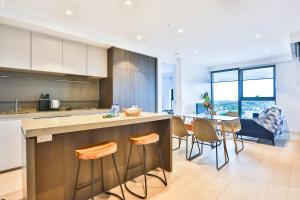 a kitchen and dining room with a counter and chairs at Box Hill Central Sky One Apartment in Box Hill