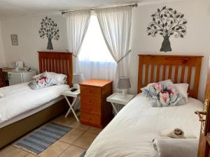 a bedroom with two beds and a desk and a window at La Bella B&B Under The Fig Tree in Bela-Bela