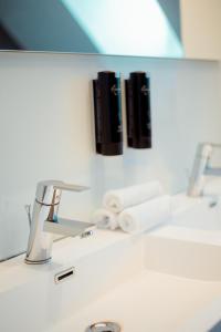La salle de bains est pourvue d'un lavabo, d'un miroir et d'un robinet. dans l'établissement Heirloom Hotels - A Flemish Tale, à Gand