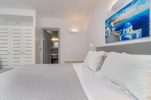費拉的住宿－Central Fira Suites，卧室配有白色的床和墙上的绘画作品