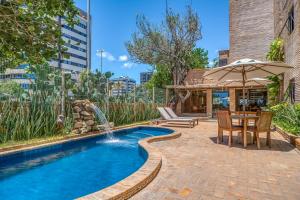 a pool with a table and chairs and an umbrella at Cais da Praia Hotel in Maceió