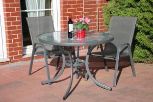 a glass table with two chairs and a bottle of wine at Ferienwohnung Boddenkieker bis 4 Personen, Sagard-Neddesitz, 70m2 in Sagard