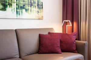 a couch with a purple pillow sitting next to a window at The Domicil Hotel Frankfurt City in Frankfurt