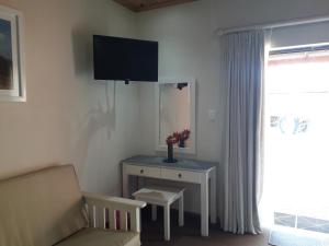 a living room with a couch and a table with a tv at Culdesac Guesthouse Oudtshoorn in Oudtshoorn
