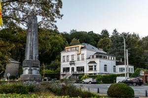 a white house with a monument in front of it at Boutique Hôtel Vedette entre Namur et Dinant in Profondeville