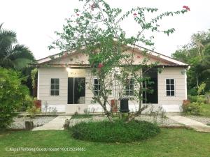 een wit huis met een boom ervoor bij Kapal Terbang Guest House Langkawi in Pantai Cenang
