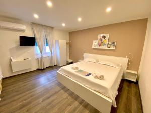 a bedroom with a white bed and a television at Mimì Rooms&Studios in Trieste