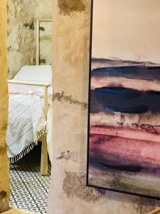 ein Gemälde, das an einer Wand neben einem Bett hängt in der Unterkunft Casa rural La Montañeta Alta in Antigua