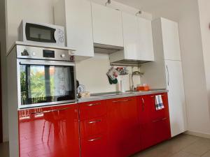 a kitchen with red cabinets and a microwave at Ennodio Apartment in Como