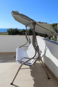 une chaise assise sous un parasol sur une terrasse dans l'établissement 90 secondi dal letto al mare, à Capo dʼOrlando