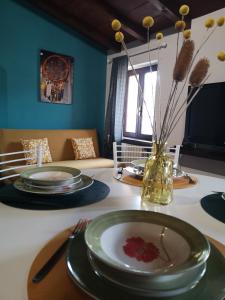 una mesa con platos y un jarrón con flores. en Borgo Fiore House, en Parma