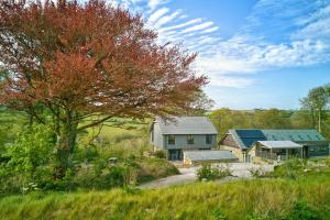 a house and a barn in a field with a tree at Glamping Yurts near Newquay in Newquay