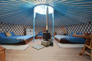 a room with a blue tent with beds and a stove at Glamping Yurts near Newquay in Newquay