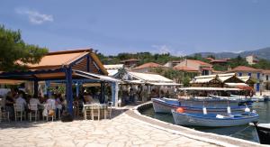 a group of people sitting at a restaurant next to the water at Drymna in Trizonia