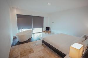 ein Schlafzimmer mit einer Badewanne, einem Bett und einem Waschbecken in der Unterkunft La Amada condo with Marina View in Cancún