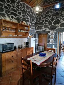 Casa do Bernardo في Feiteira: مطبخ مع طاولة طعام وجدار حجري