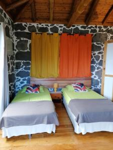 two beds in a room with a stone wall at Casa do Bernardo in Feiteira