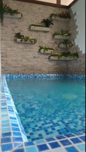 a swimming pool with blue tiles in front of a brick wall at Estet Hotel in Essentuki