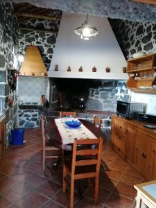 a kitchen with a table and a stone wall at Casa do Bernardo in Feiteira