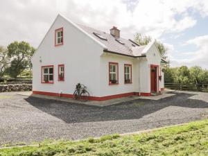 una casa blanca con una bicicleta delante en Lough Mask Road Fishing Cottage, en Cong