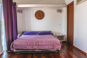 ein Schlafzimmer mit einem Bett mit einer lila Decke in der Unterkunft Attico con terrazza unico in Cagliari