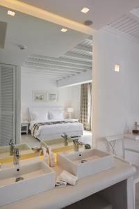 a white bathroom with two sinks and a bed at Petinos Beach Hotel in Platis Yialos Mykonos