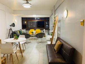 a living room with a couch and tables and yellow chairs at Kings View in Margate