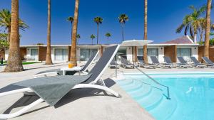 a swimming pool with lounge chairs and palm trees at Sanom Beach Resort Only Adults in Playa del Ingles