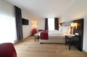 Habitación de hotel con cama y silla roja en Hotel La Prairie, Swiss Bike Hotel, en Yverdon-les-Bains