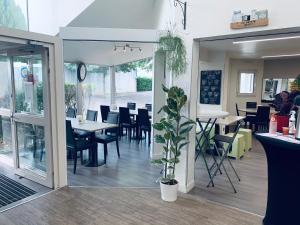 um restaurante com mesas e cadeiras e um vaso de plantas em Hotel Inn Design Dijon Sud em Marsannay-la-Côte