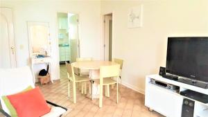 a living room with a table and a television at Riviera São Lourenço Acqua in Bertioga