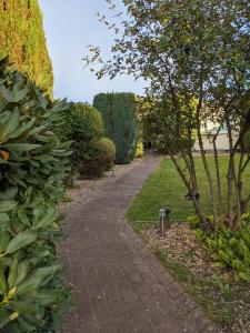 a walkway in a park with a tree and bushes at Privatzimmer Sutanto in Reppenstedt