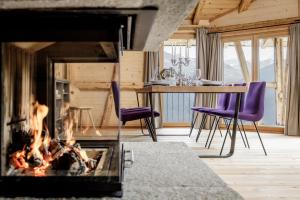 a living room with a fireplace and a table with purple chairs at Leni Mountain Chalet in Sölden