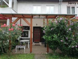 a pergola in front of a house with flowers at Éva Vendégház in Bük