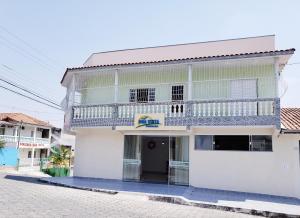 um edifício branco com uma varanda numa rua em Pousada Boa Vista em Cachoeira Paulista