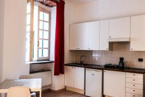 una cucina con armadietti bianchi e una tenda rossa di Via Argelati - Navigli Top Location 2 a Milano